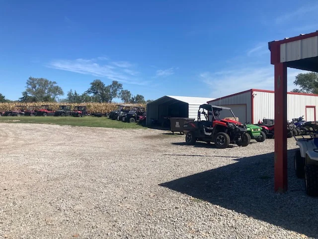 Gravel parking area beside the Olive Creek shop with ATVs and side-by-sides around the lot