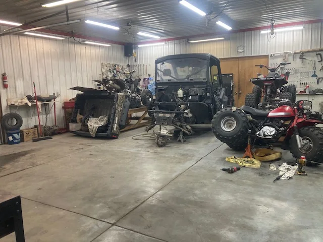 ATVs and a side-by-side being worked on inside the Olive Creek repair bay